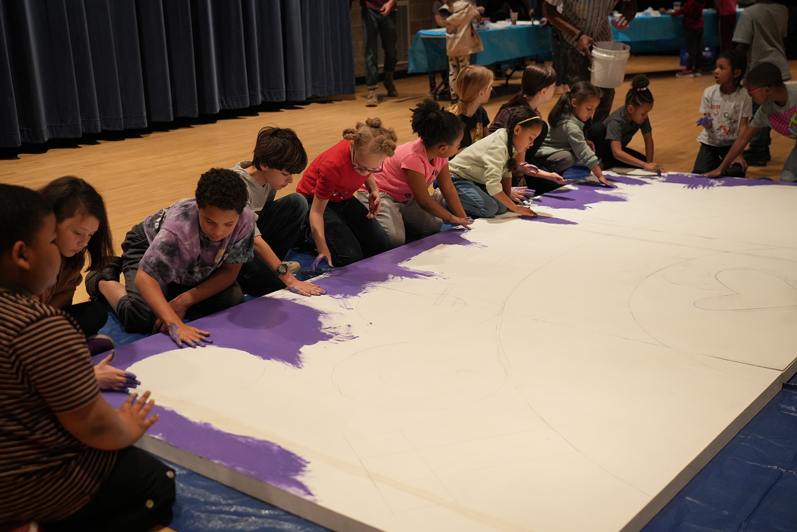 Children paint canvas for Nehemiah “Nemo” Edwards "Together We Thrive" piece.